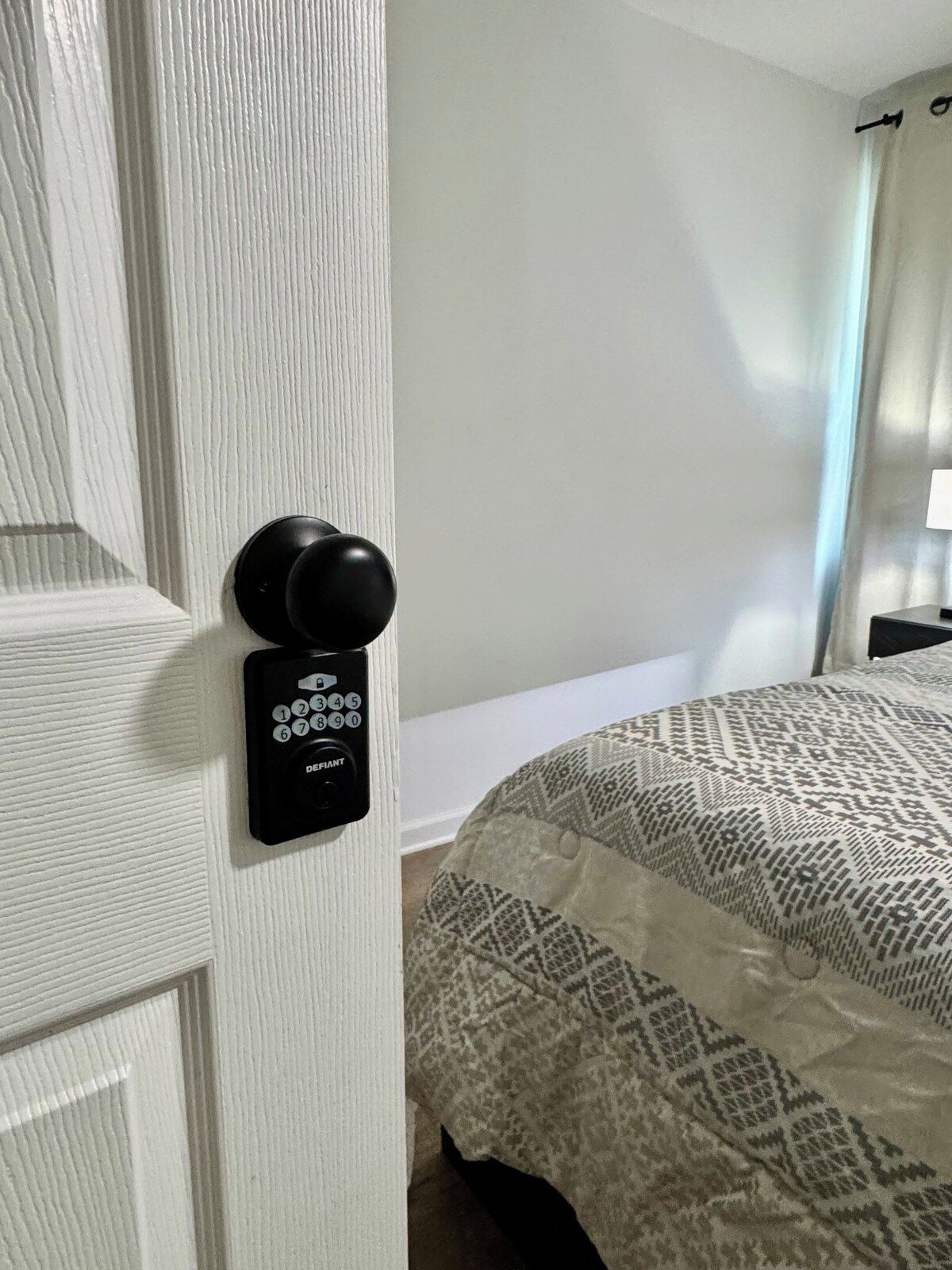 A room with a door equipped with a keypad lock and a round doorknob.