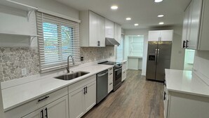 A modern kitchen with white cabinets, a stainless steel refrigerator, and a stone backsplash.