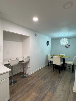 A modern kitchen with white cabinetry, a dining area with a round table and chairs, and a decorative light fixture. - Peachtree Executive Home — Luxury 4BR 2 Primary Suites, Sleeps 9 Near Charlotte (Gastonia)