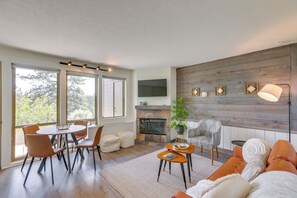 Ein modernes Wohnzimmer mit Kamin, Essbereich und einer Couch.