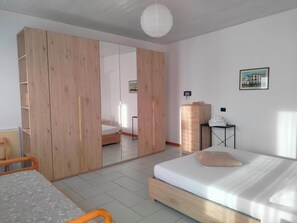 Ein Schlafzimmer mit Holzschrank, Bett mit Kissen, Nachttisch und Spiegel.