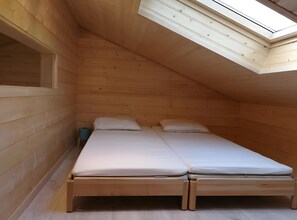 A small, wooden room with a sloped ceiling and a skylight, containing a single bed with two pillows. - Holiday Home “La Cabane – Bassin d’Arcachon” with Shared Pool and Private Garden (Gujan-Mestras)
