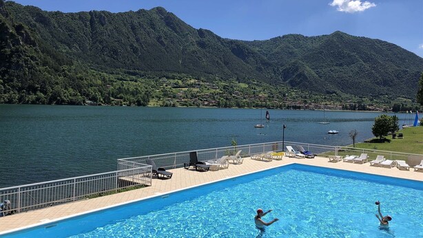 Ein Schwimmbad mit Blick auf einen See und Berge.