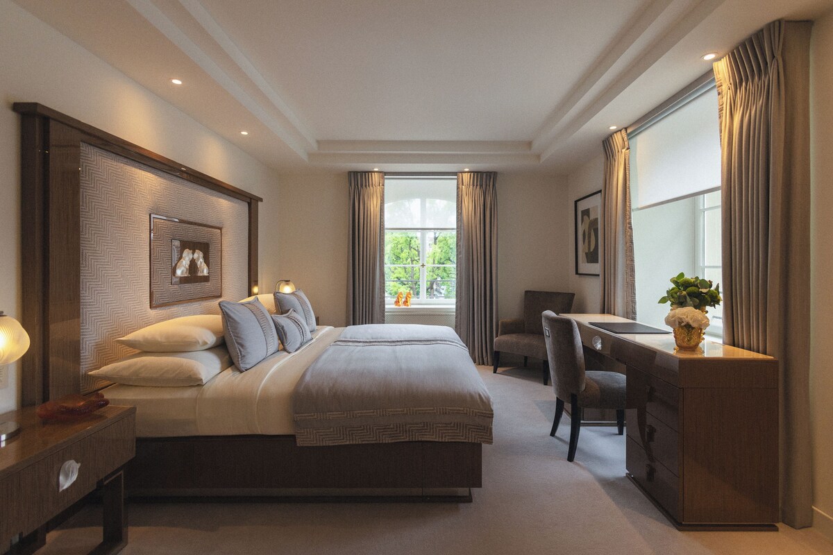 A hotel room with a bed, a desk, a chair, and a window with curtains.
