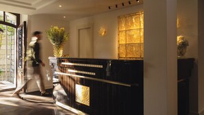 Ein Hotel-Empfangsbereich mit einem Holzbüro, einem Blumenstrauß und einer dekorativen Wandverkleidung.