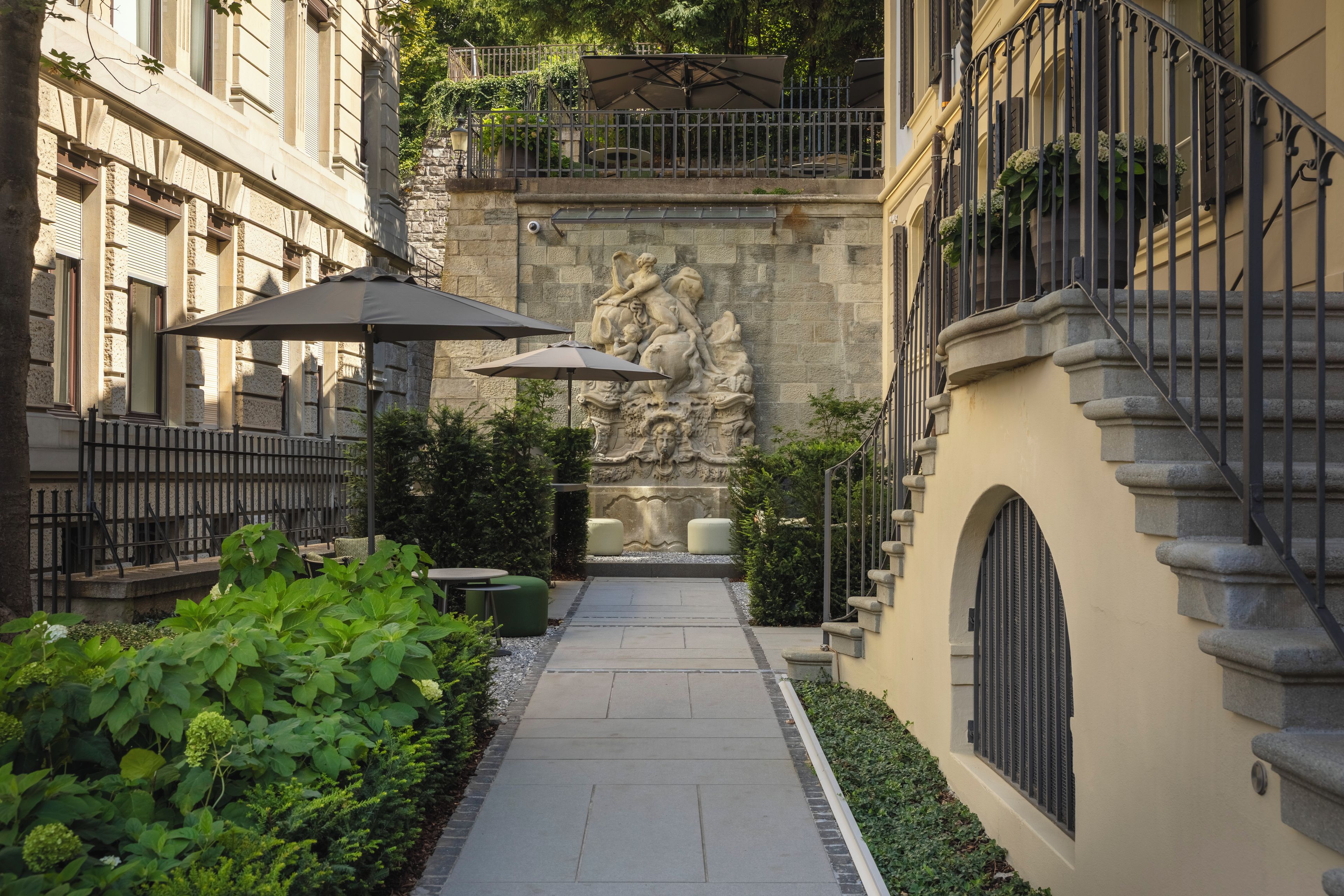 Un patio con una estatua de piedra, mobiliario exterior y un sendero.