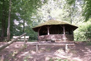 Eine rustikale Holzhütte mit einem Reetdach, umgeben von Bäumen.