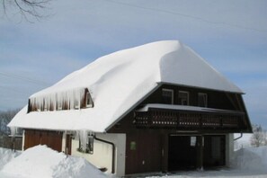 Ein zweistöckiges Gebäude mit verschneitem Dach und Holzfassade.