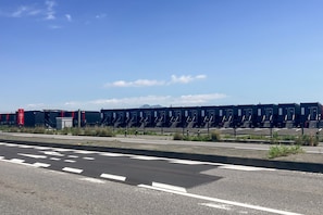 Uma estrada com faixa de pedestres e uma fileira de edifícios semelhantes ao fundo.