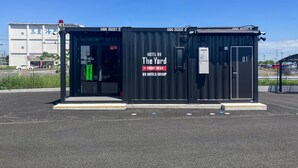 A black container-style hotel named 'The Yard' with a front desk, part of the R9 Hotels Group. - HOTEL R9 The Yard Joso (Joso)