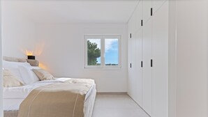 A bedroom with a bed, a nightstand, a window, and a wardrobe. - Crown Penthouse Čiovo (Okrug Gornji)