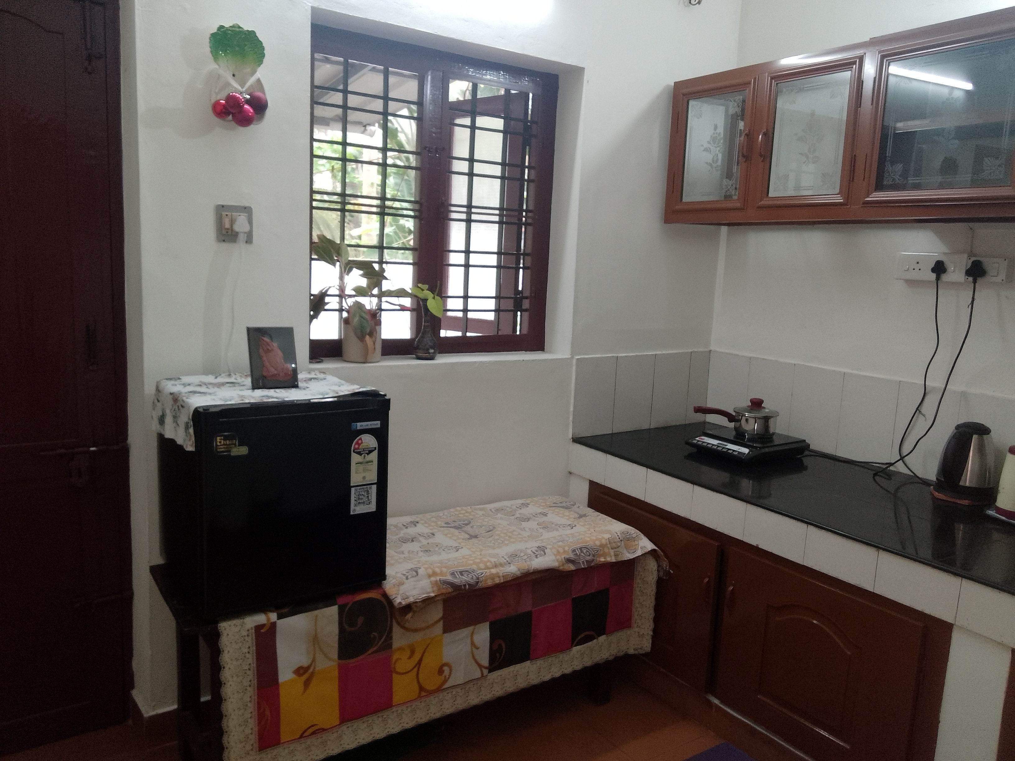A compact kitchen with a refrigerator, a stove, and a window with a view of greenery outside.