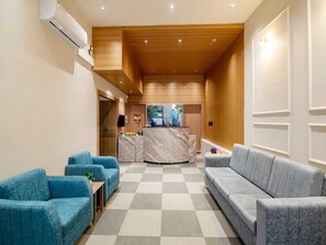 Een hotel lobby met een zwart-wit schachbordvloer, een receptiebalie en zitgedeeltes.
