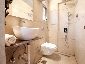 Een moderne badkamer met een groot wit wastafel, toilet en douche.