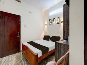 Ein Schlafzimmer mit einem hölzernen Bett, einem Kleiderschrank, einem Schreibtisch mit Stuhl und Wandleuchten.
