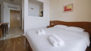 A hotel room with a large bed, a wooden headboard, a small desk, and a mirror. - Villa Sunce Podgora -studio apartment 2 (Podgora)