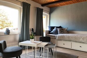 Ein Schlafzimmer mit Bett, Schreibtisch, Stuhl und einem Fenster mit Vorhängen.