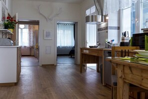 Una cocina con suelo de madera, una mesa de comedor y vista a un dormitorio por una puerta abierta.
