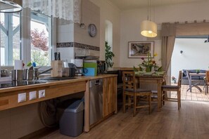 A kitchen with wooden cabinets, a dishwasher, a sink, and a dining area with a table and chairs.