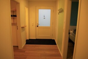A narrow hallway with a door at the end, a doormat, and a coat rack to the right. - Holiday home with 2 bedrooms (Klein Wittensee)
