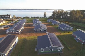 A residential area with multiple houses, some with solar panels, and a body of water in the background. - Holiday home with 2 bedrooms (Klein Wittensee)
