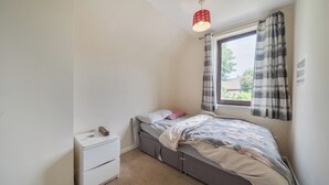 A bedroom with a bed, a nightstand, a window with curtains, and a ceiling light. - 2 Bed House - Sleeps 4 - Parking - Wifi (Sheffield)