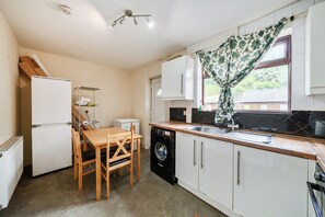 Cocina compacta con lavadora, mesa de comedor y refrigerador.