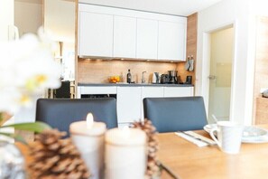 Eine moderne Küche mit weißen Schränken, einer Holzauskładung und einem Essbereich mit zwei Stühlen und einem Tisch.