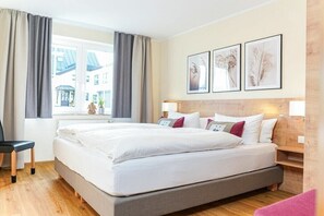 A hotel room with a large bed, a chair, a desk, and a window with curtains. - Holiday apartment with 1 bedroom (Kurort Oberwiesenthal)