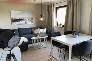 Ein modernes Wohnzimmer mit einer Couch, einem Esstisch und einem kleinen weißen Tisch.