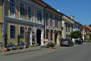 Calle con edificios históricos, un letrero de un negocio local y coches estacionados.