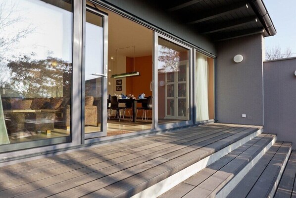 A modern building with large glass doors leading to an interior space with a dining area.