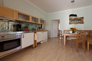 Une cuisine avec des meubles de rangement en bois, une cuisinière et une table à manger avec des chaises.
