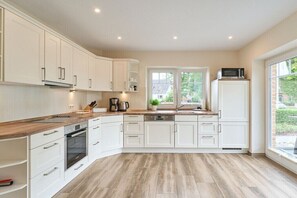 Eine moderne Küche mit weißen Schränken, einer Holz Arbeitsplatte und einem eingebauten Ofen.