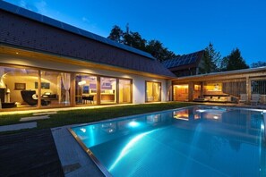 Ein modernes Haus mit Schwimmbad, großen Fenstern und einem gut beleuchteten Innenraum.