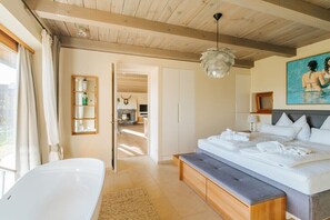 Ein Schlafzimmer mit einem großen Bett, einer Bank, einer Badewanne und einer Holzbalkendecke.