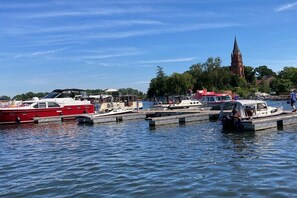 A marina with boats docked, a church in the background, and a clear sky. - Holiday apartment with 1 bedroom (Röbel\/Müritz)