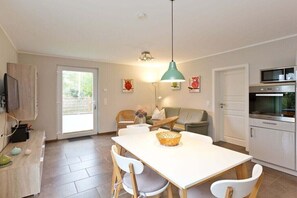 A modern kitchen with a dining table, chairs, a hanging light fixture, and a microwave. - Holiday apartment with 1 bedroom (Röbel\/Müritz)