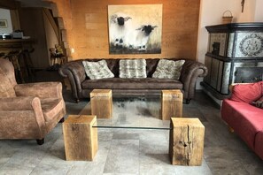 Ein Wohnzimmer mit einem braunen Sofa, einem Glastisch und Holzschemeln.