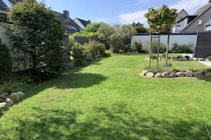 Ein gepflegter Garten mit Rasenfläche, Bäumen und einer Steingrenze.