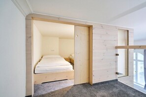 A bedroom with a bed, a wooden wardrobe, and a window. - Holiday apartment with 1 bedroom (Steinberg)