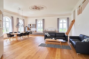 Ein großzügiger Wohnbereich mit Esstisch, Sofas und einer Küche im Hintergrund.