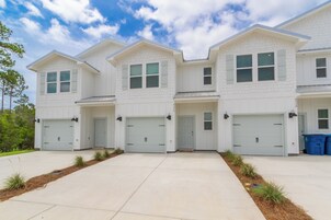 A multi-story residential building with a symmetrical facade, multiple garage doors, and a well-maintained driveway.