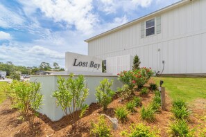 A building with a sign reading 'Lost Bay' and a landscaped garden with various plants. - Lost Bay Hideaway (Orange Beach)