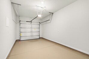 Um quarto limpo e vazio com porta de garagem em estrutura metálica, paredes brancas e chão bege.