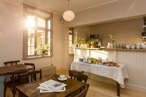 A dining area with a table set for breakfast, a radiator, and a window with plants. - Rheinsberg in the Lexow Manor House (Walow OT Lexow)