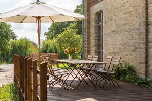 An outdoor patio with a table and chairs, a wooden fence, and a brick building in the background. - Rheinsberg in the Lexow Manor House (Walow OT Lexow)