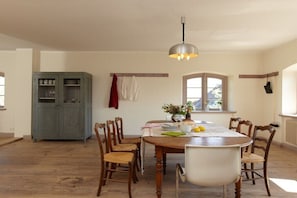A dining area with a wooden table, chairs, a hanging light fixture, and a cabinet. - Luisenfeld in the Lexow Manor House (Lexow)