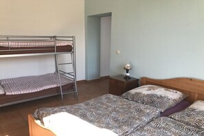 Ein Zimmer mit Etagenbetten, einem Nachttisch mit Lampe und einer gemusterten Bettdecke.