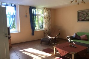 Ein Wohnzimmer mit einer Couch, einem Sessel, einem kleinen Tisch und einem Fernseher.
